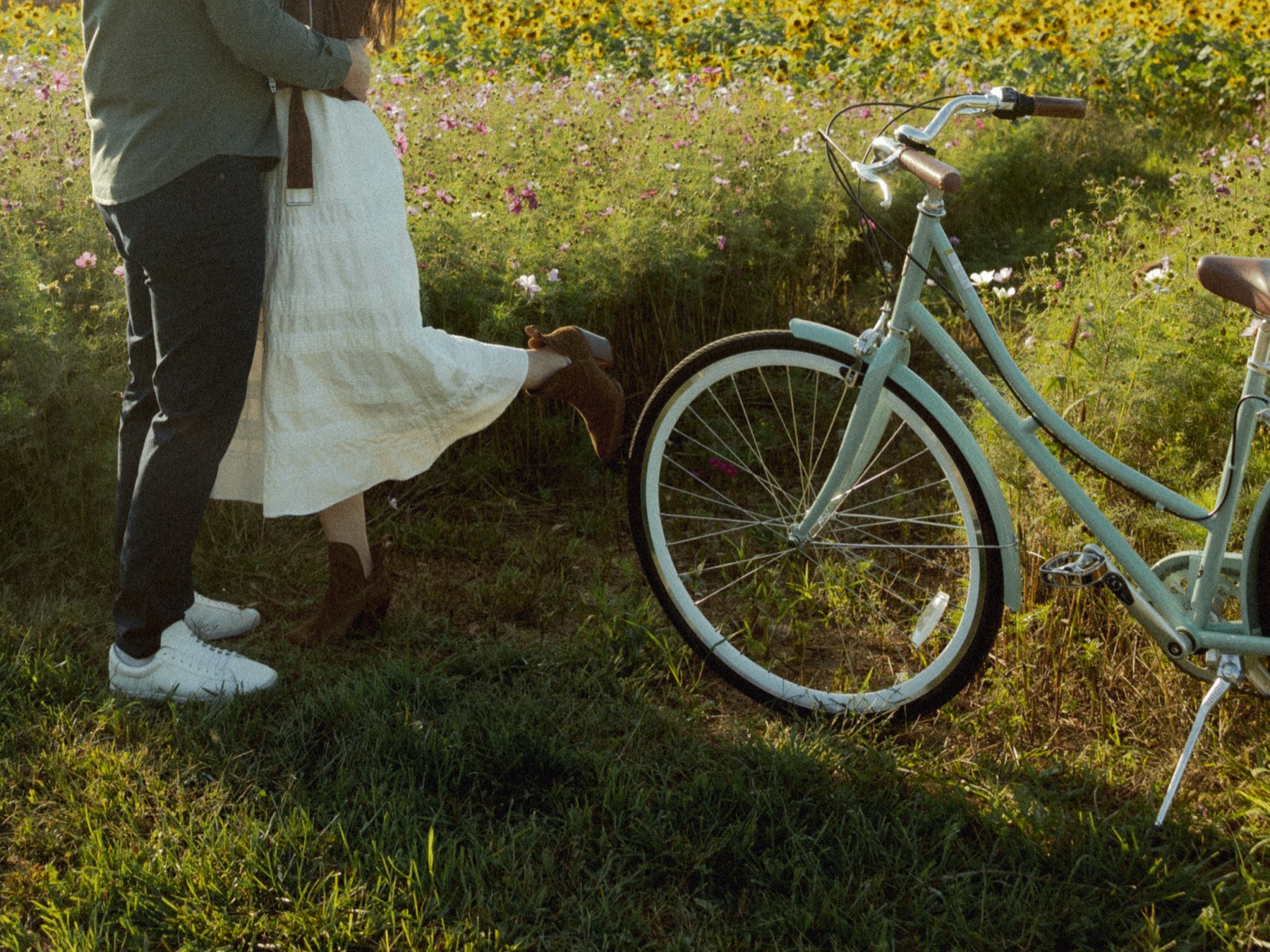 A couple embracing in a field of wildflowers beside a mint bicycle